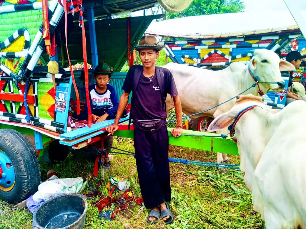 "Bajingan" Cilik - Andre (11) bersama adiknya, salah satu peserta event dari pedukuhan Tirto, kelurahan Bangunjiwo, kecamatan Kasihan, kabupaten Bantul, Yogyakarta sedang berpose di gerobak sapinya, di lapangan Morangan atau lapangan Sport Center, Kelurahan Caturharjo, Kabupaten Sleman, Yogyakarta, Minggu (2/11/2025) (Foto: Dok MI/Gatot Eko Cahyono)