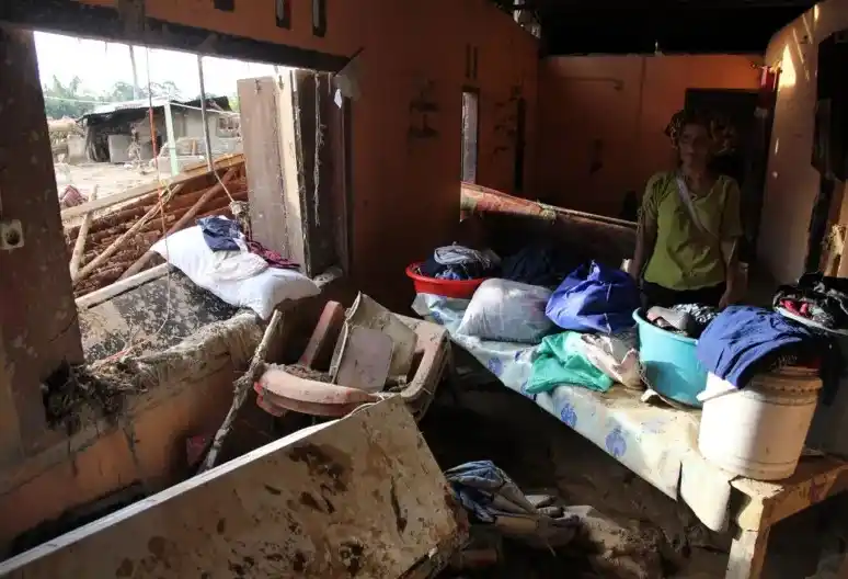 Seorang perempuan berdiri di dalam rumahnya yang hancur di Tapanuli Selatan, Sumatra Utara, pada Minggu (30/11/2025)