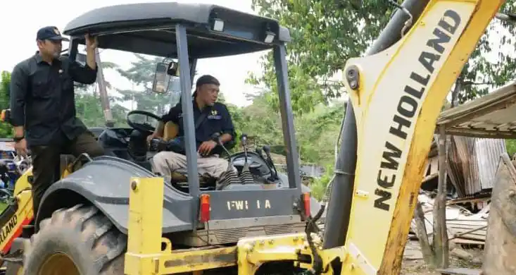 Bupati Merangin, HM Syukur (kiri) turut menumpangi alat berat pada pembongkaran belasan rumah bordil di kawasan Jalinsum Kabupaten Merangin, Provinsi Jambi, baru-baru ini. (Foto : Ist).