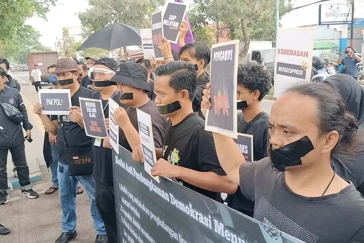Puluhan jurnalis di Jambi menggelar aksi solidaritas damai dengan menutup mulut menggunakan lakban hitam dan membawa poster protes di depan Mapolda Jambi, Rabu (17/9/2025).