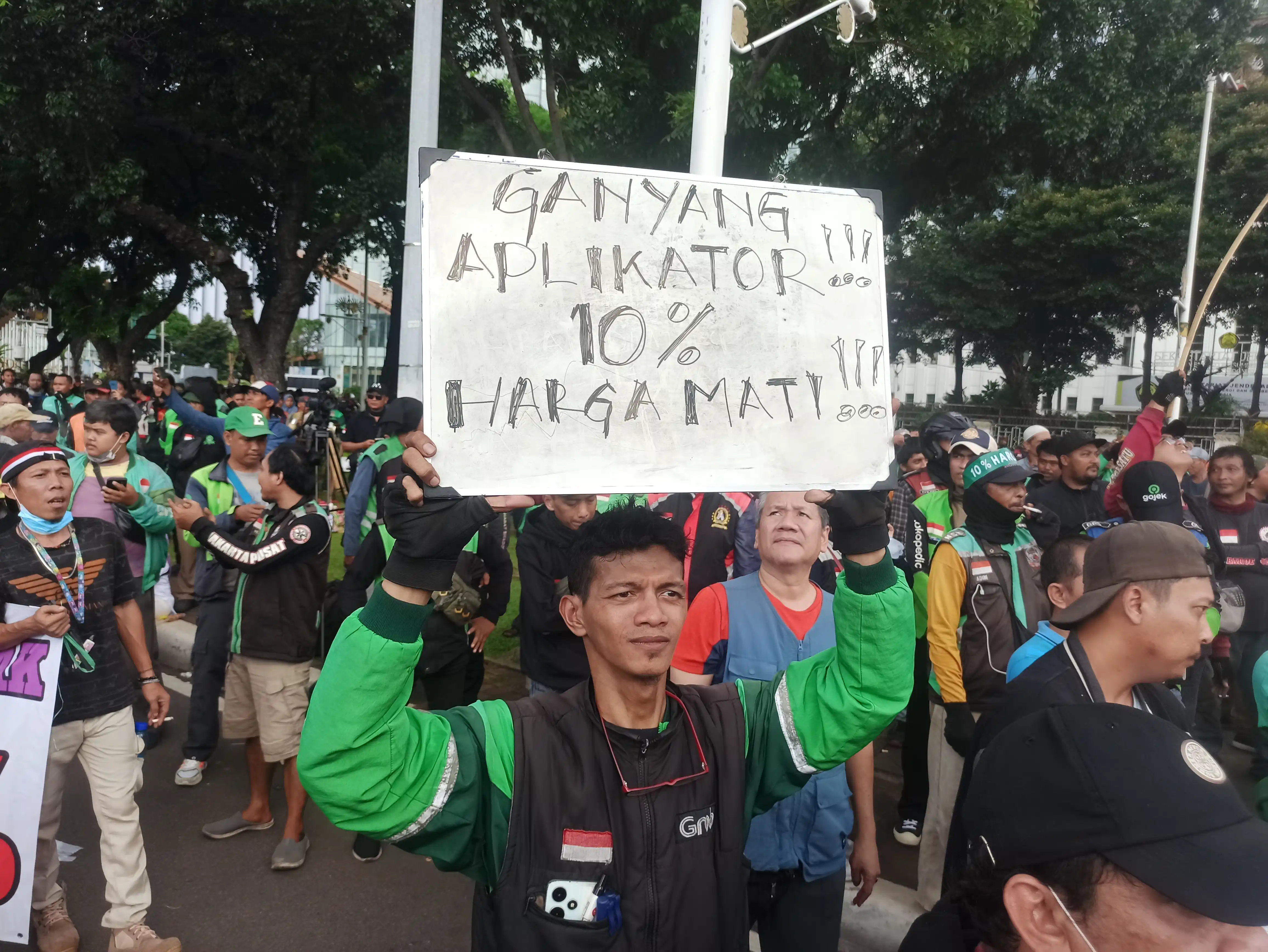 Salah satu peserta aksi unjuk rasa pengemudi ojek online membawa papan tulis bertuliskan "Ganyang Aplikator!!! 10% Harga Mati" (Foto: Dok MI/Alb)