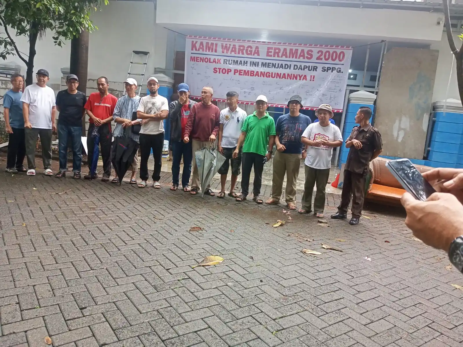 Warga Perumahan Eramas 2000 di Pulogebang, Jakarta Timur, menggelar aksi penolakan pembangunan Dapur MBG melalui penandatanganan spanduk petisi. Mereka menegaskan tidak menolak program pemerintah, namun meminta lokasi dipindahkan dari permukiman padat karena dikhawatirkan menimbulkan dampak lingkungan seperti limbah, bau, dan kemacetan. Warga berharap pemerintah mengkaji ulang lokasi dan membuka dialog untuk mencari solusi terbaik.